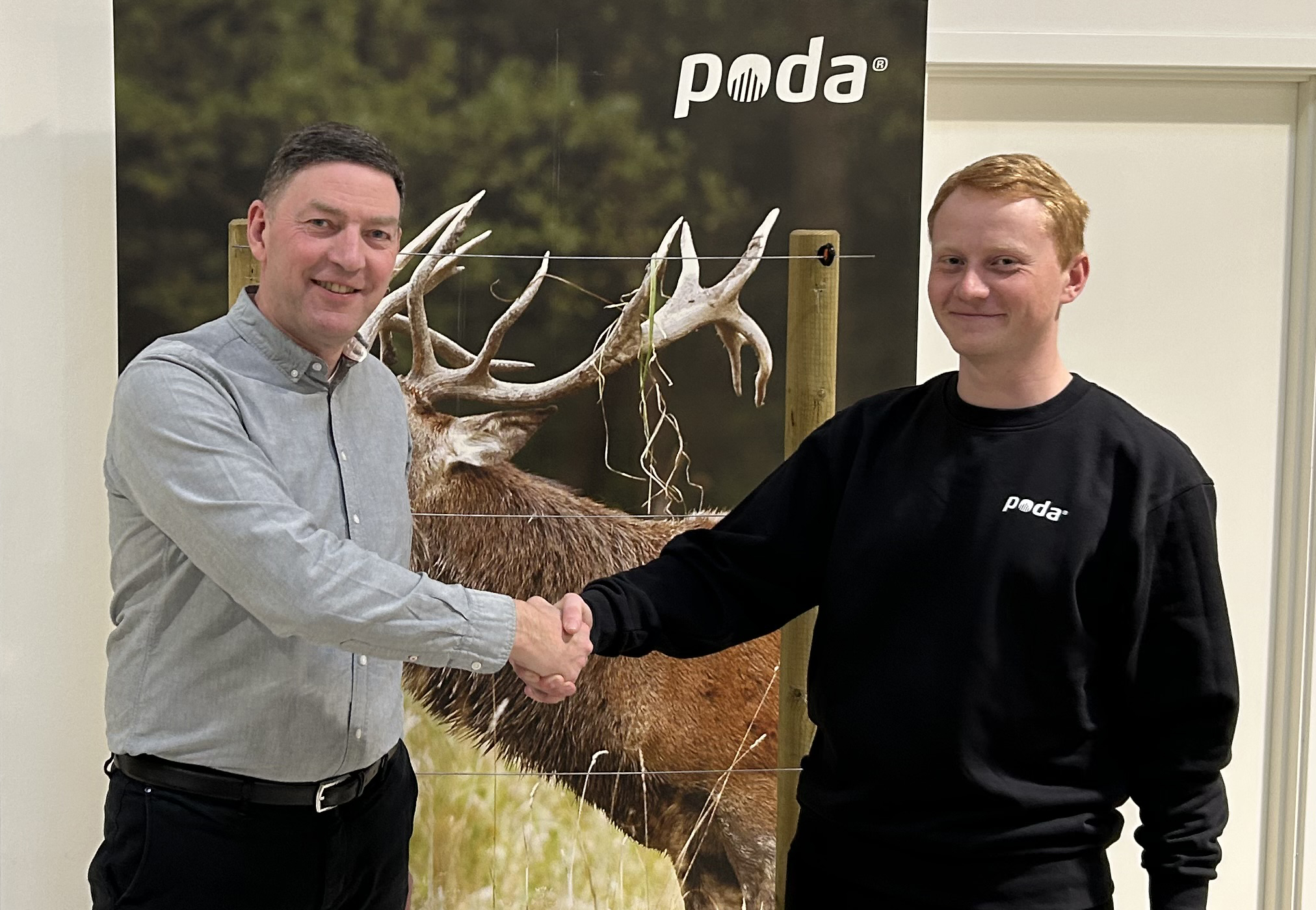 Poda-directeur Peter schudt de hand van Sofus van het nieuwe Poda-centrum, Poda Hegn Ringe, voor een banner met een edelhert en schrikdraad.