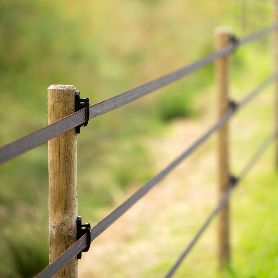 Twee afrasteringspalen verbonden met band vormen een driestrengs paardenafrastering.