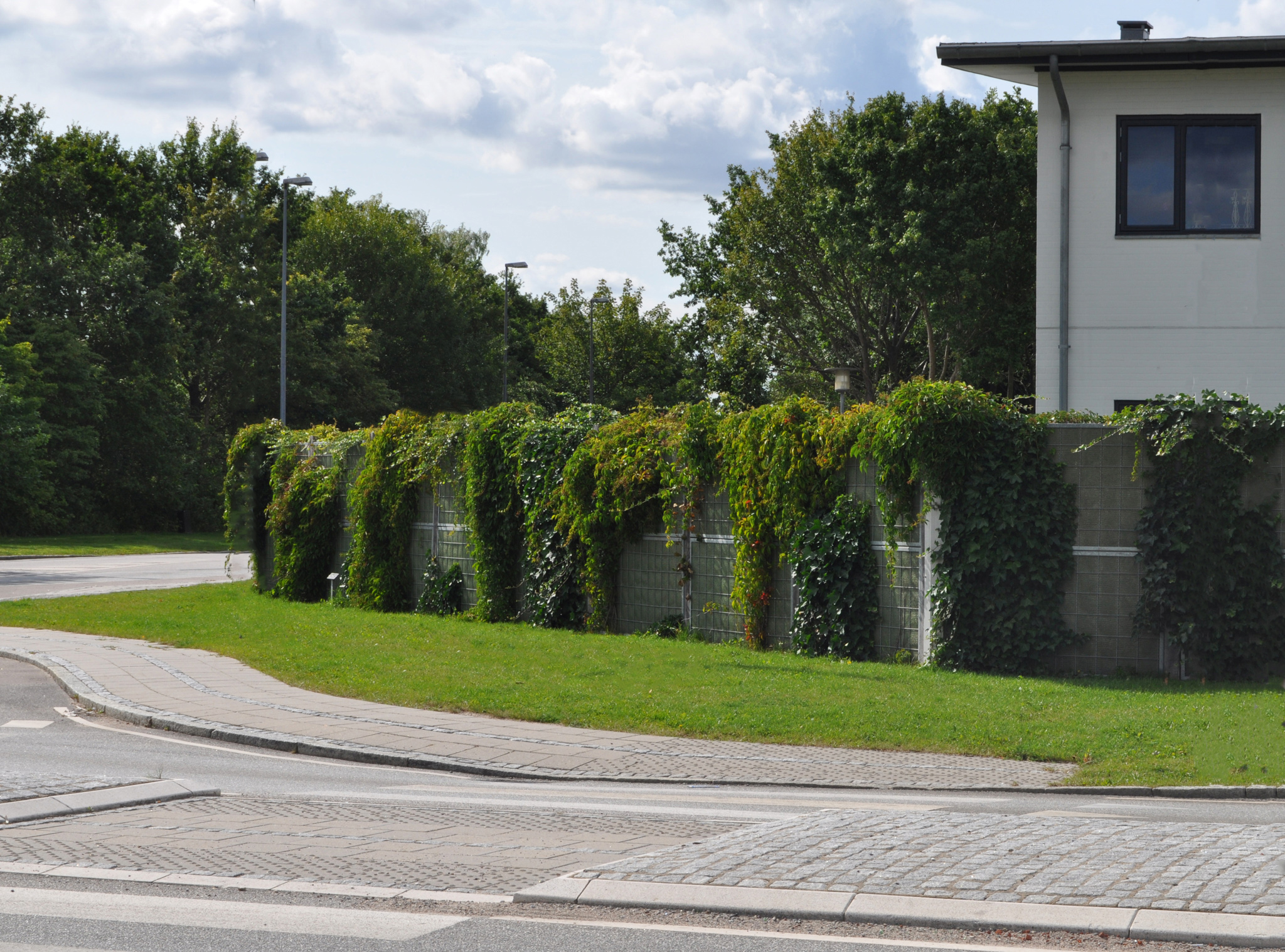 Een prachtig geplaatst Noistop® Steel geluidsscherm van Poda Omheiningen dat een huis beschermt tegen verkeerslawaai van een grote openbare weg