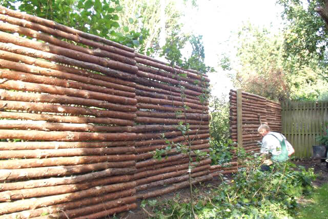 Een man installeert een omheining van sparrenhout