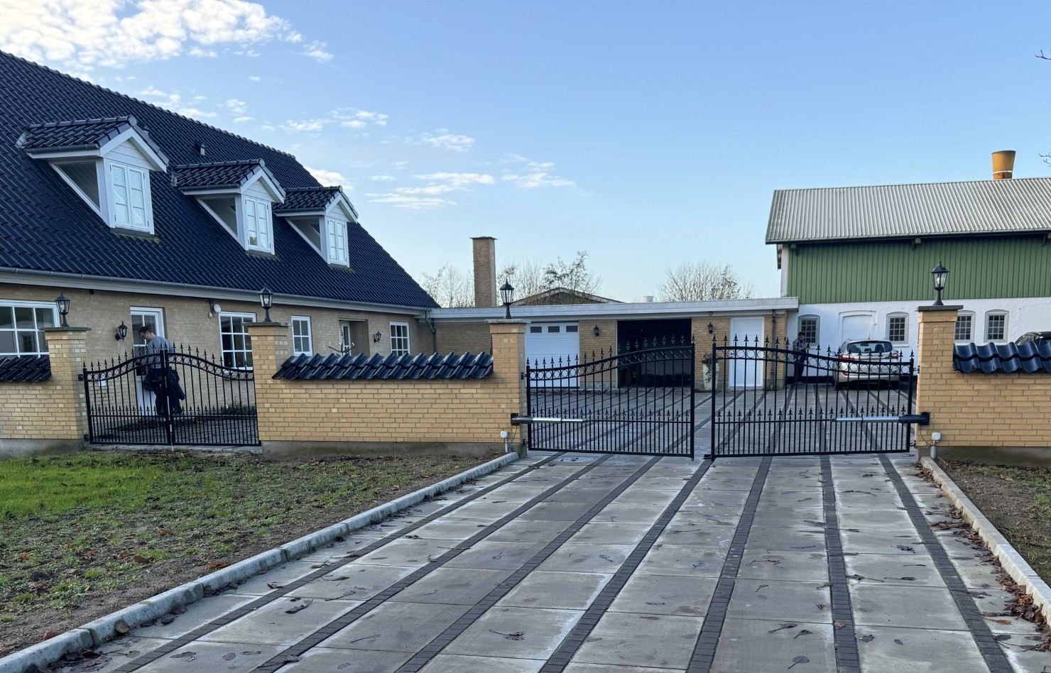 De automatische poort opent op de oprit en de smeedijzeren poort aan de linkerkant wordt gebruikt als voetgangerspoort.