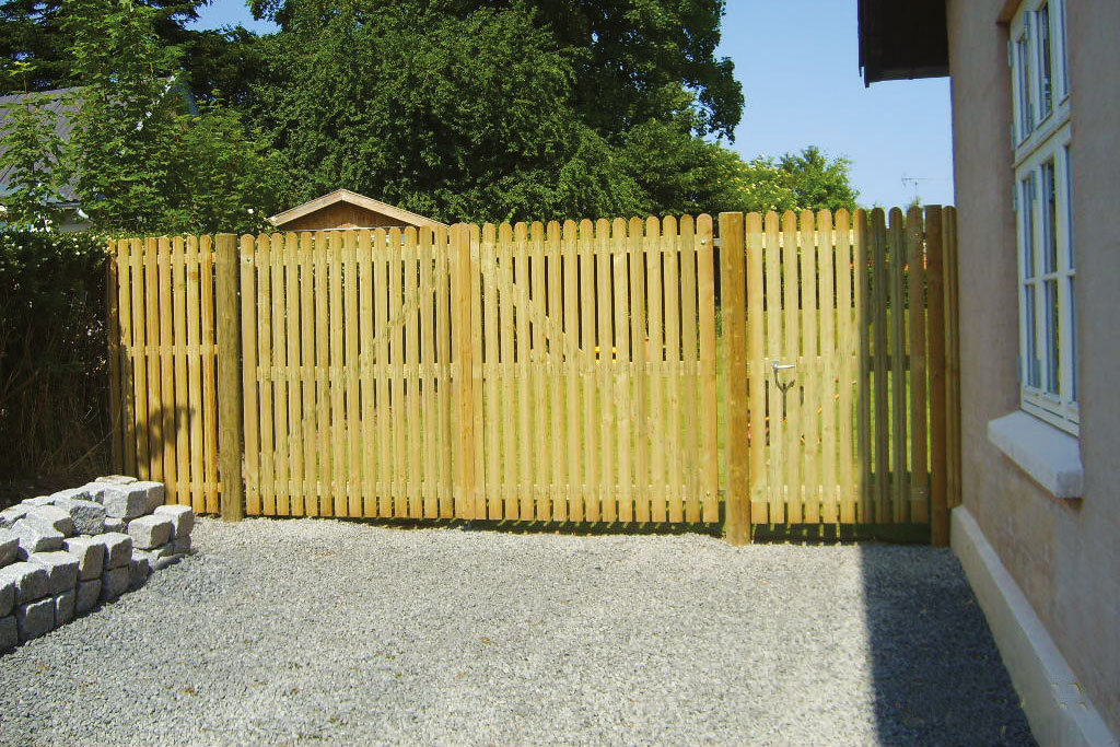 Een hoge dubbele poort en een loophek vormen de ingang tot een tuin